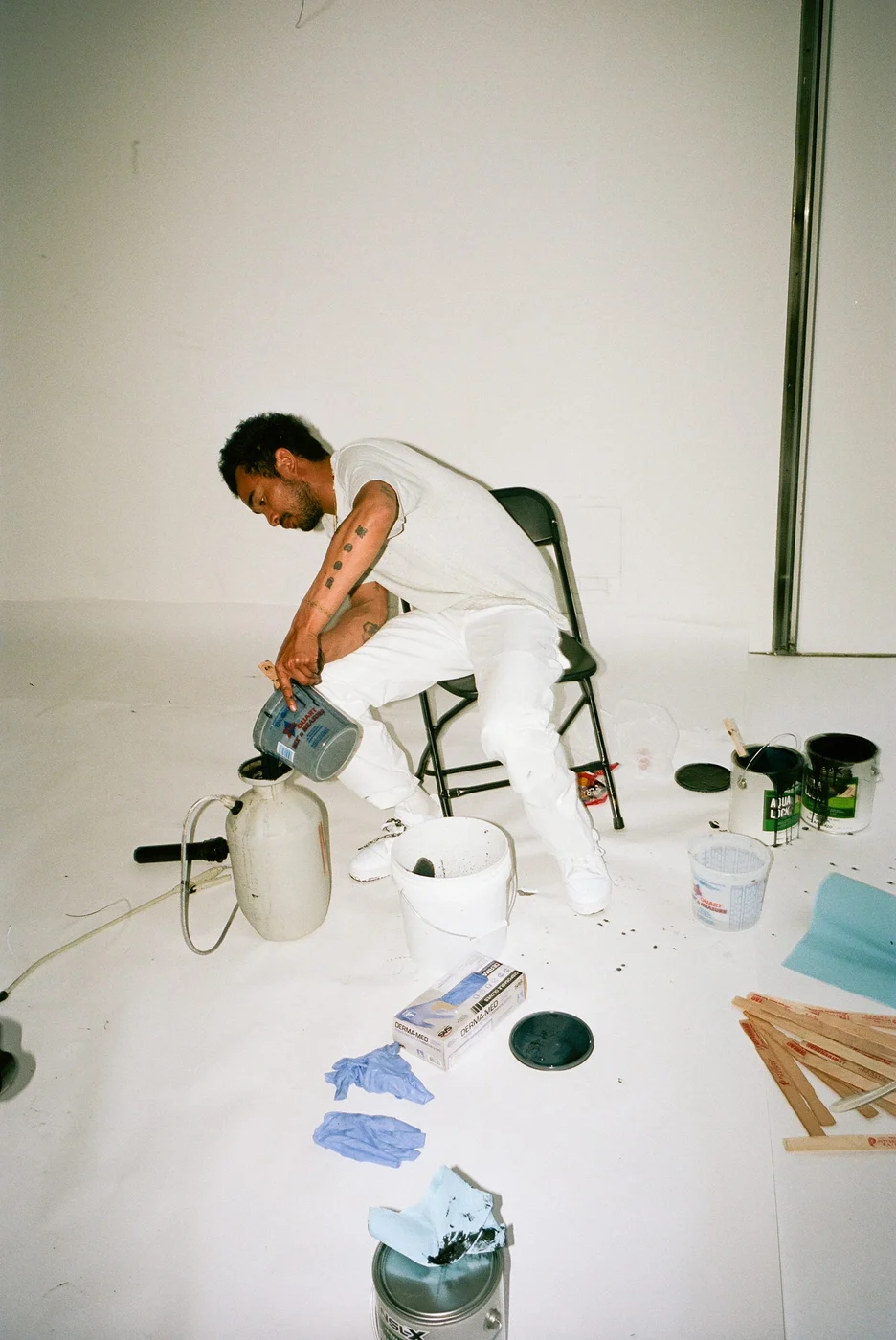 Lucien Smith working beside paint buckets and a fire extinguisher in his studio