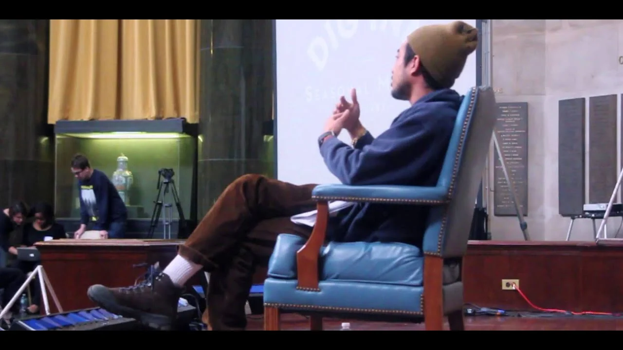 Lucien Smith seated on stage, mid-sentence, during his TEDxColumbiaCollege talk